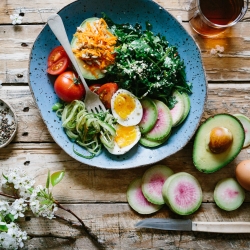 Plate of food on a rustic table with eggs, veggies and salad