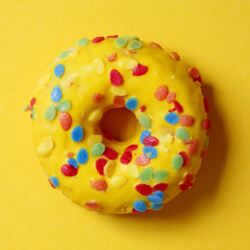 Bright yellow glazed donut with multicolored sprinkles