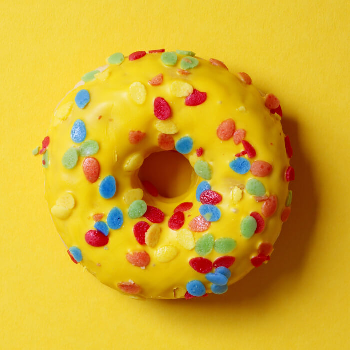 Bright yellow glazed donut with multicolored sprinkles