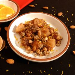 Apple Crisp on a plate with toasted almonds and sprinkled with orange zest