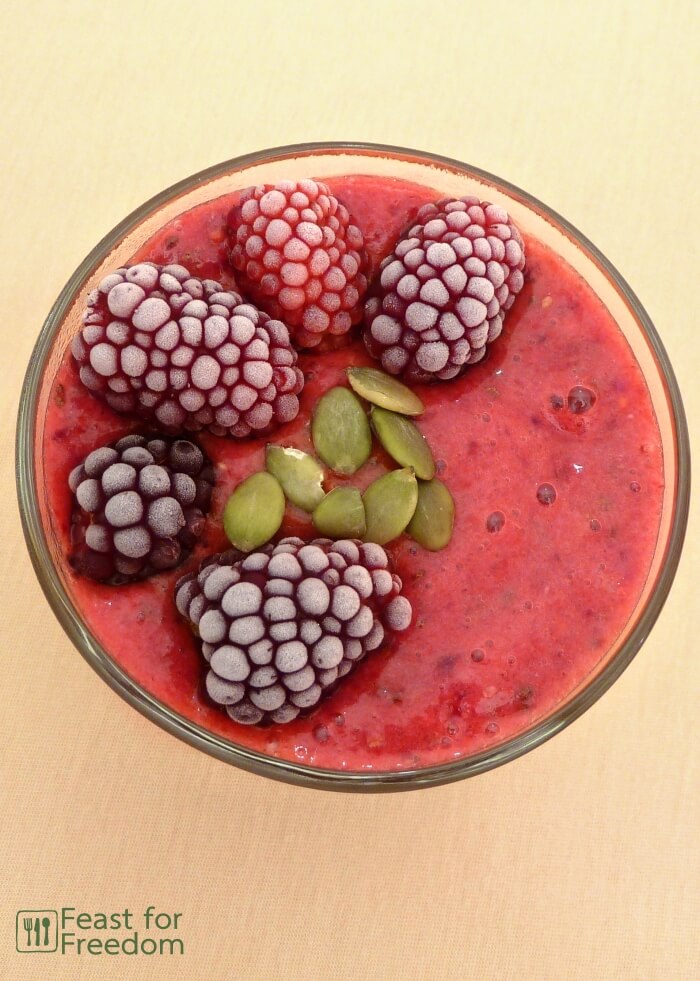 Blackberry smoothie topped with frozen blackberries and seeds