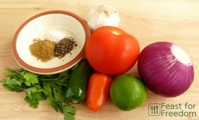 Fresh ingredients to make salsa - tomatoes, jalapenos, lime, onion, garlic, parsley, spices