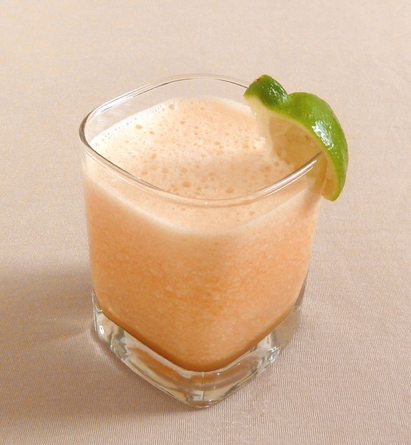 Cantaloupe smoothie in a glass with a lime garnish
