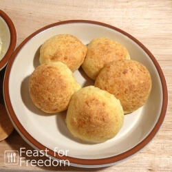Cheese buns on a plate next to a small dish of butter