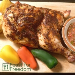 Baked chicken basted with fresh salsa on a wooden cutting board