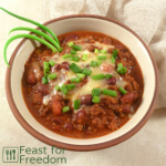 Bowl of chili with grated cheese and green onions
