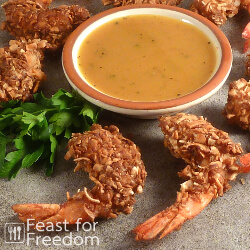 Coconut shrimp on a platter with honey mustard sauce in a small bowl