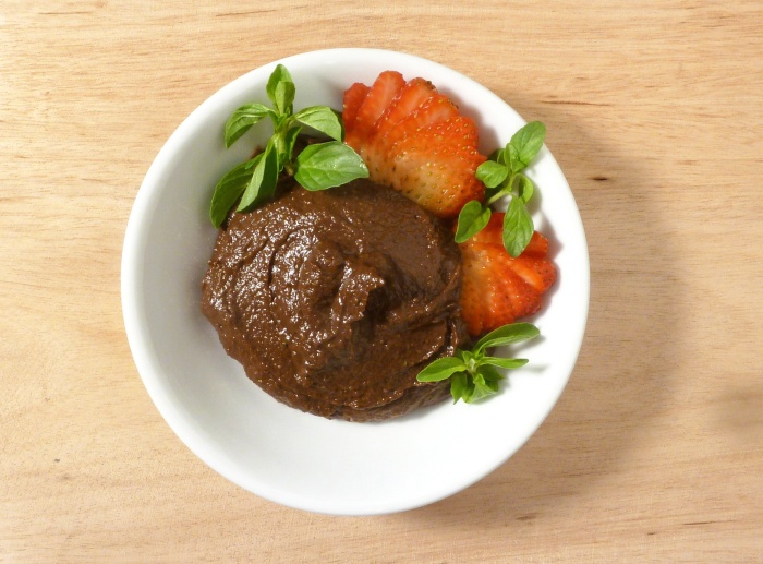 Chocolate mousse in an dish, topped with mint leaves and strawberries