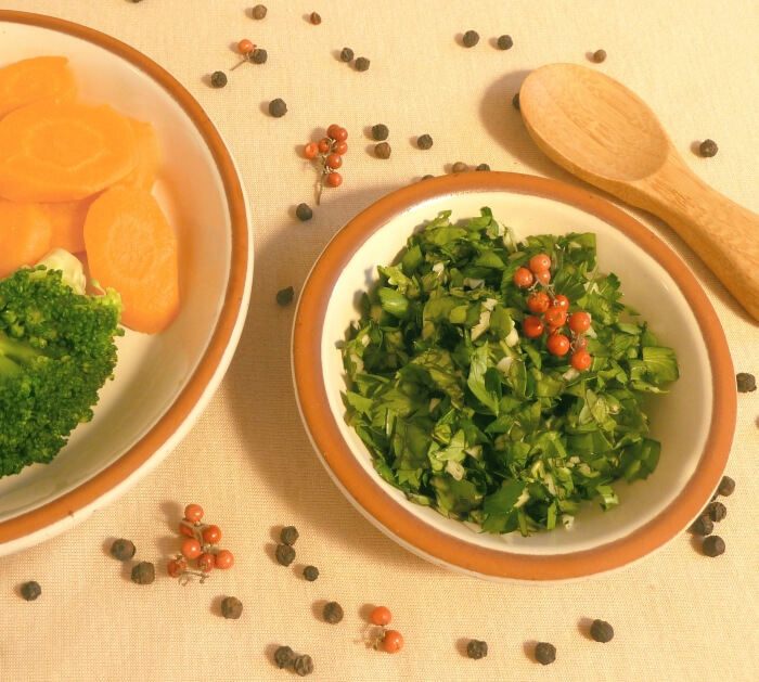 Herb sprinkle made from fresh herbs on a plate next to steamed veggies