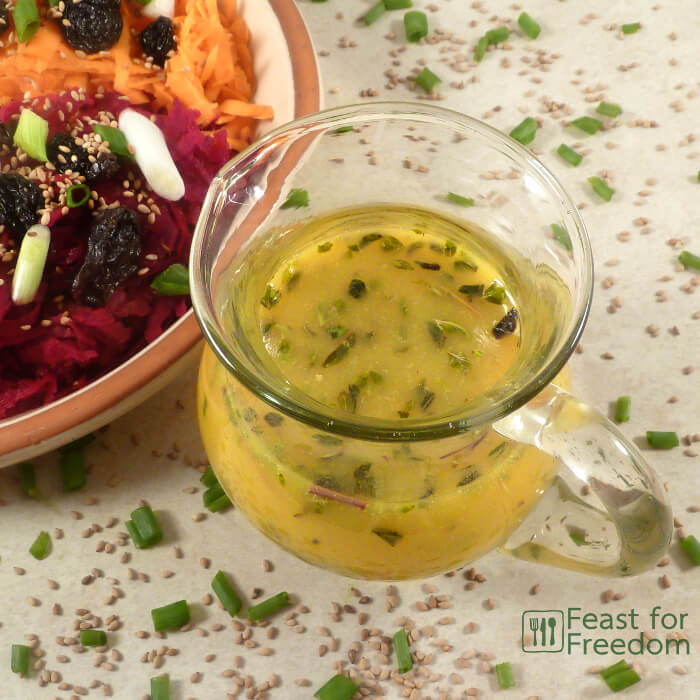 Honey mustard dressing in a small jug next to a veggie salad