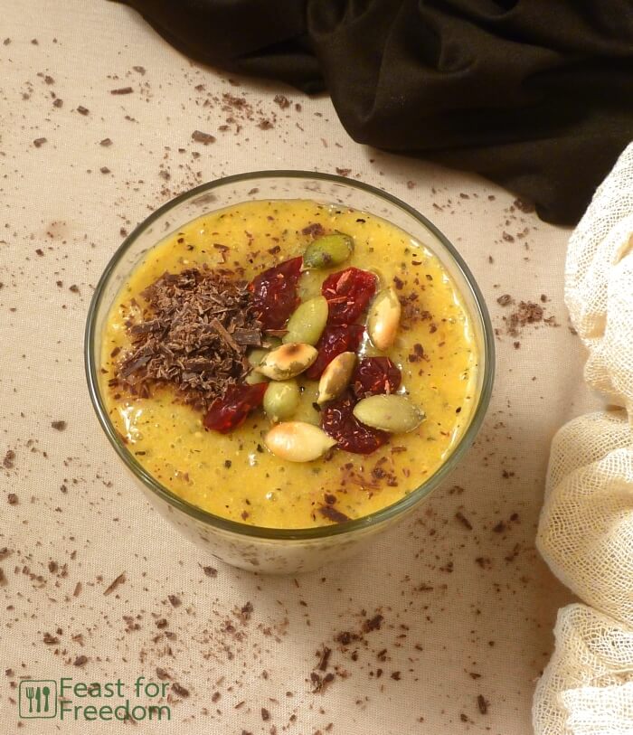 Smoothie made with dragon fruit, bananas and mango, garnished with seeds, dried cranberries and shredded chocolate