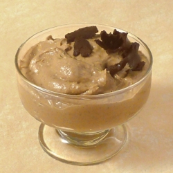 Nut butter and banana pudding in a simple bowl, topped with large grated chocolate chunks
