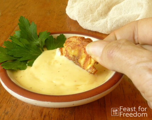 Pan fried green plantains being dipped into garlic mayo
