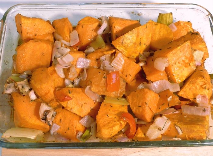 Roasted sweet potatoes with onions and red pepper in a baking dish