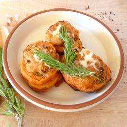 Sweet potato stackers on a plate sprinkled with Parmesan cheese and a sprig of fresh rosemary