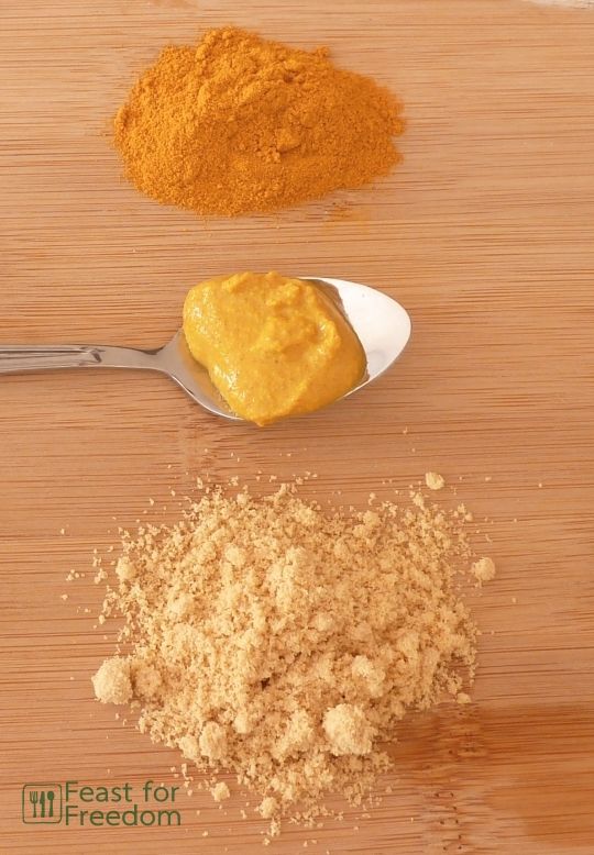Yellow mustard on a spoon next to small piles of turmeric and mustard powder
